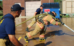 Fire fighter carrying the spraying hose, keeping the water jet aimed forward.