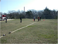 Fire fighter getting ready to run the length of the hose, and connect 2 ends.