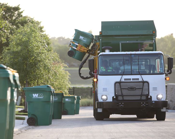 Waste Management truck picking up trash can.